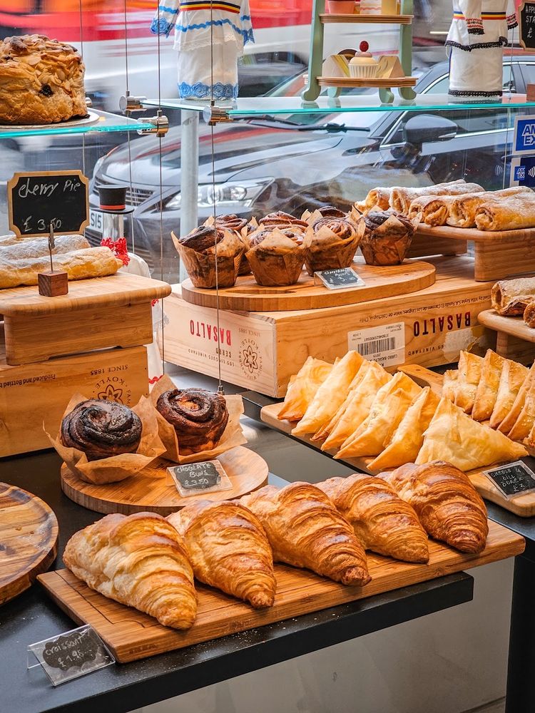The display cabinet loaded with croissants, pain au chocolat, buns and pastries on wooden boards